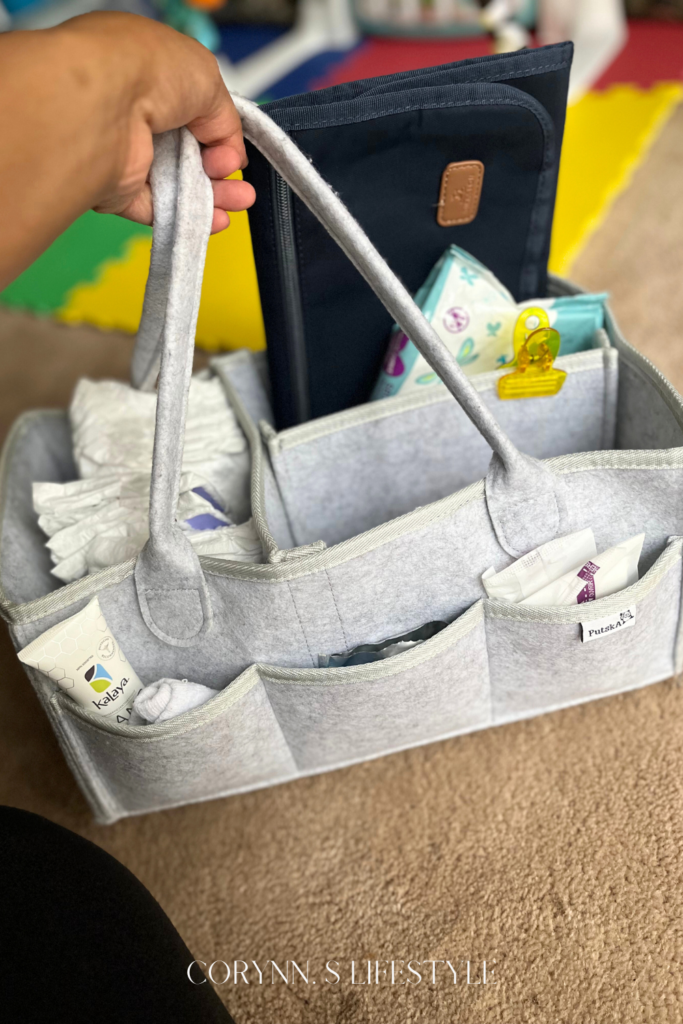 Photo of a grey diaper caddy filled with diaper changing supplies, hand sanitizer, nursing pads. 