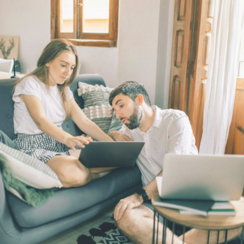 couple sitting together look at each others laptop. Non-kitchen registry ideas